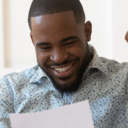 man reading a piece of paper, excited to receive his tax return