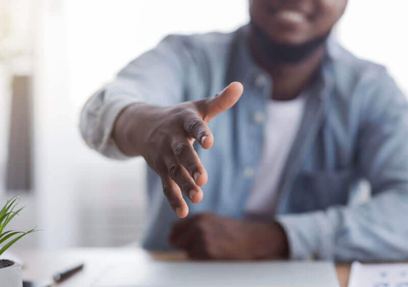  black man in job interview offering congratulatory handshake