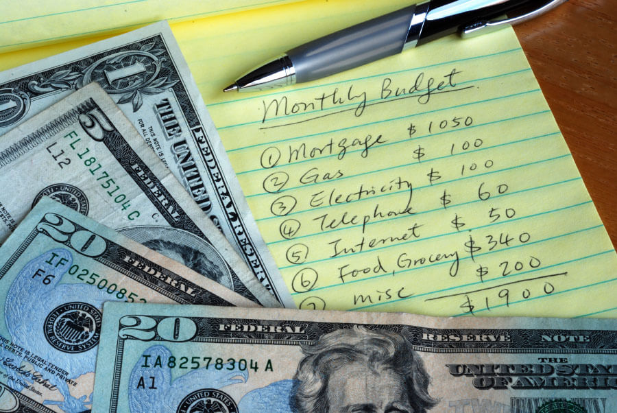 handwritten monthly budget list next to paper currency